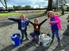 Three children with buckets of trash in a park