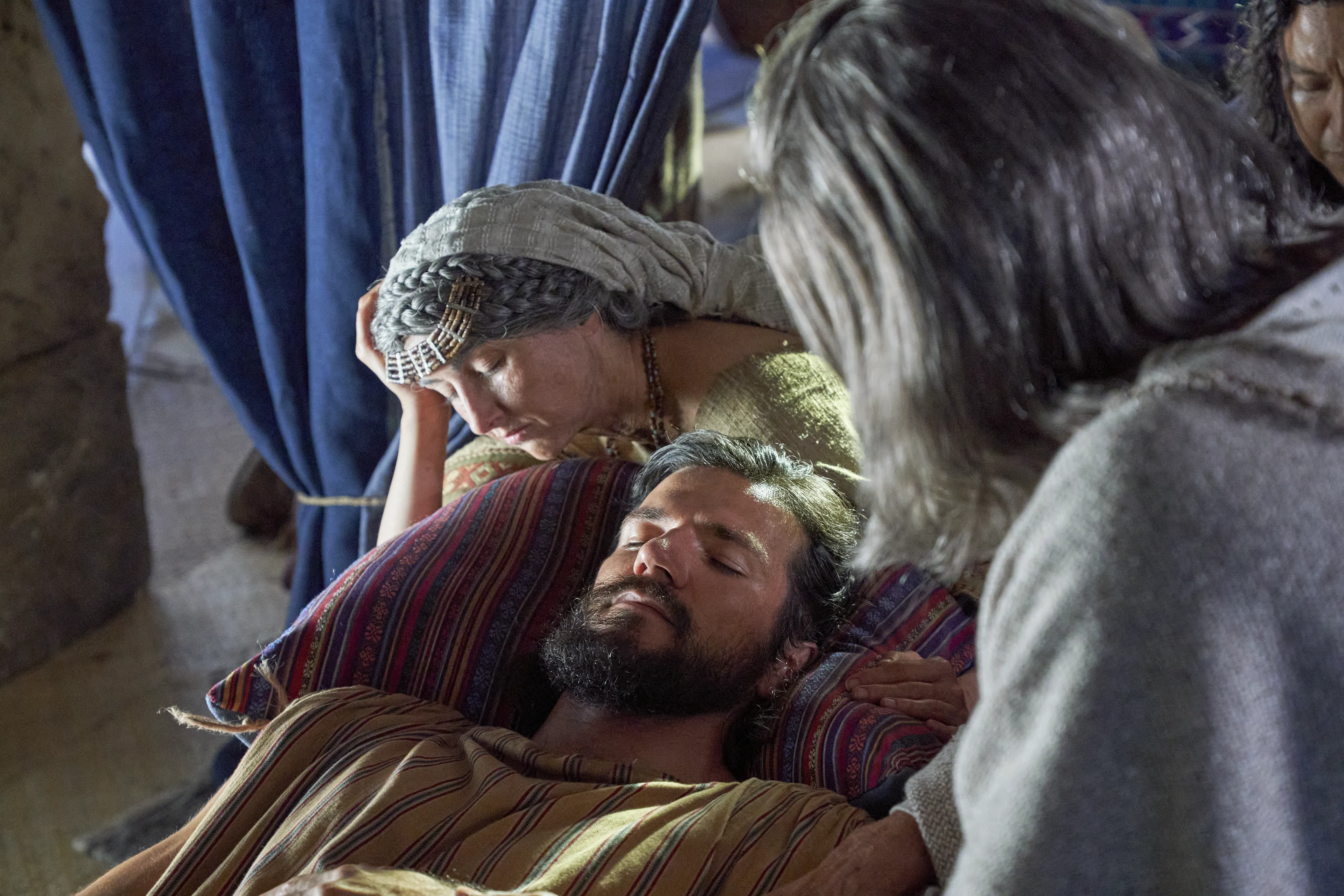 Alma the Younger lies in bed while his parents attend him.