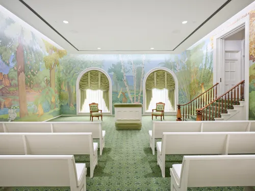 Interior image of the Manti Utah Temple. The image focuses on the Ordinance room. You see pews in the room. Around the walls are murals.