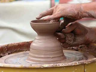 hands shaping pottery at a wheel