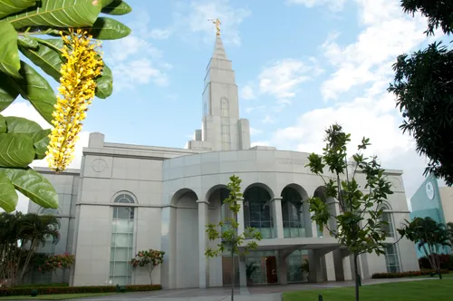 The Recife Brazil Temple, with trees growing on the grounds and small white clouds overhead.
