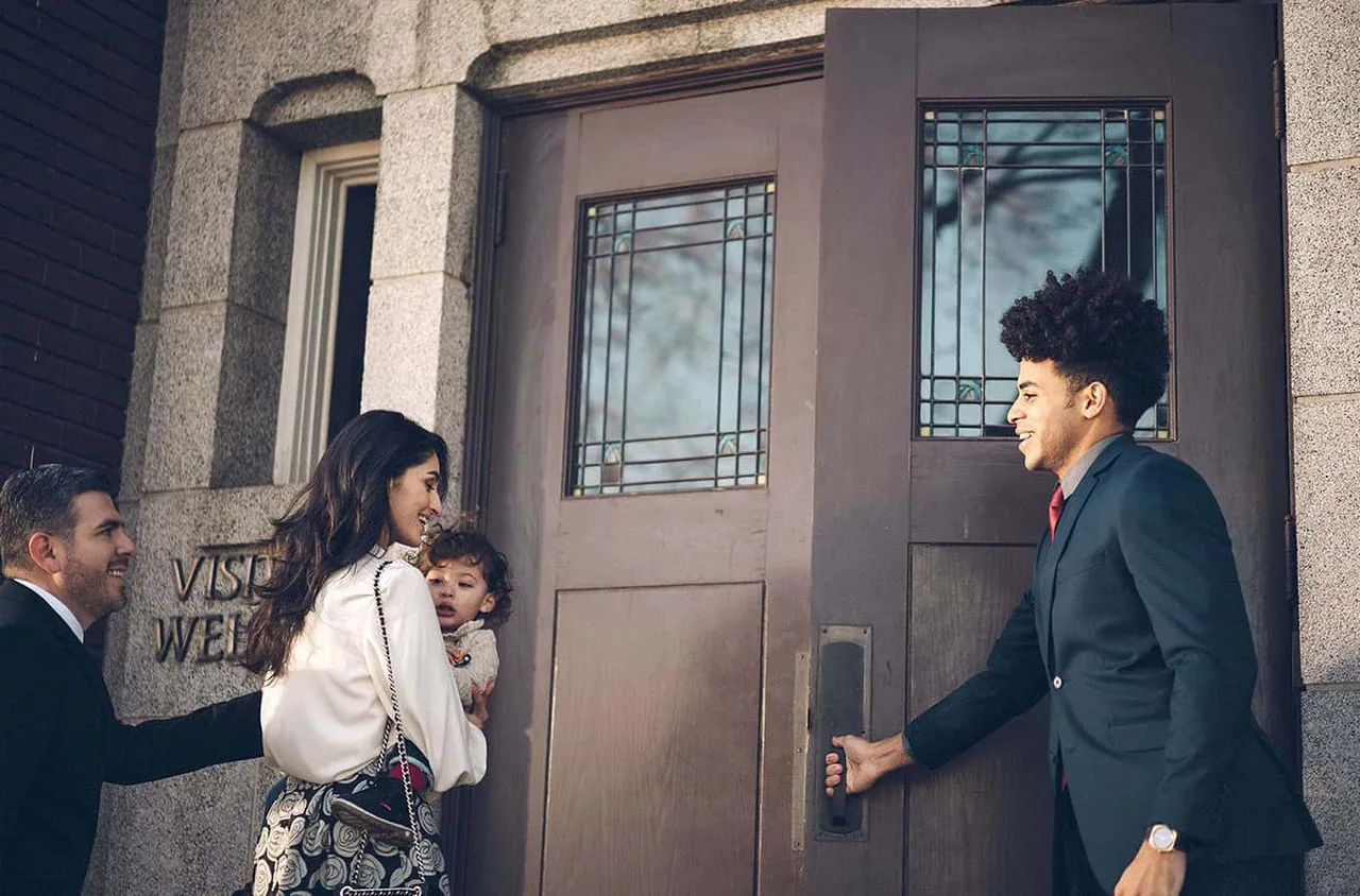 A man holds a door open for a young family into a church to learn about Jesus Christ