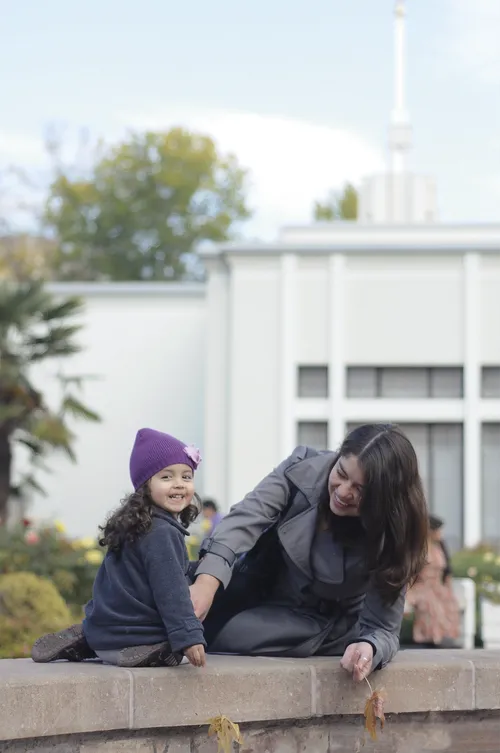 Día de Templo.  A woman and a young girl playing on a wall outside the Santiago Chile Temple.