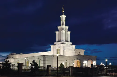 The Columbia River Washington Temple at night, with the lights illuminating it against the deep blue background of the night sky.