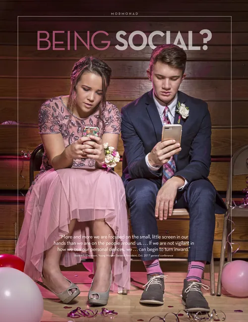 Two teenagers sit on the sidelines at a dance, ignoring each other and staring at their phones.