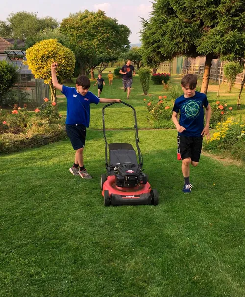 Two boys pushing a lawn mower