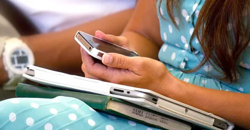 young woman holding laptop and phone