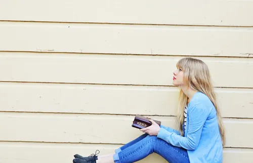 a woman holds a set of scriptures and looks into the distance