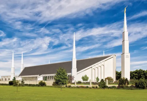 A side view of the Boise Idaho Temple during the daytime, set against a blue sky and white clouds.