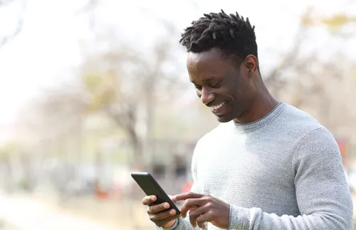 young man smiling while looking at a cell phone