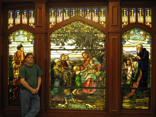 Tom Holdman standing in front of a stained glass window.