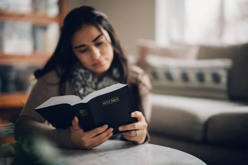 A woman studies the Bible in her living room finding strength in versus