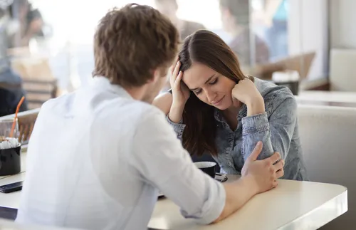 young man reaching out to young woman across a table