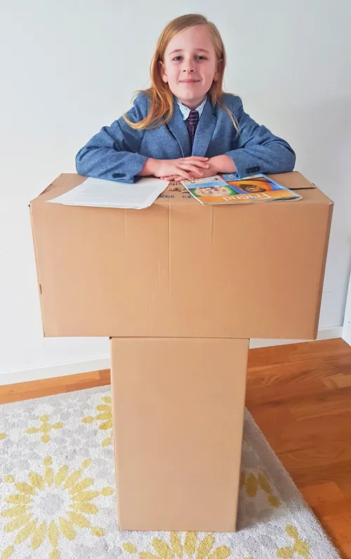boy standing behind cardboard podium