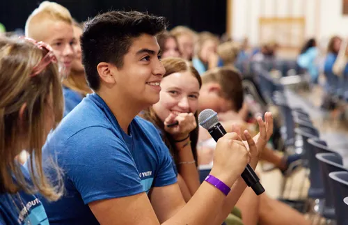young man holding a microphone in a class