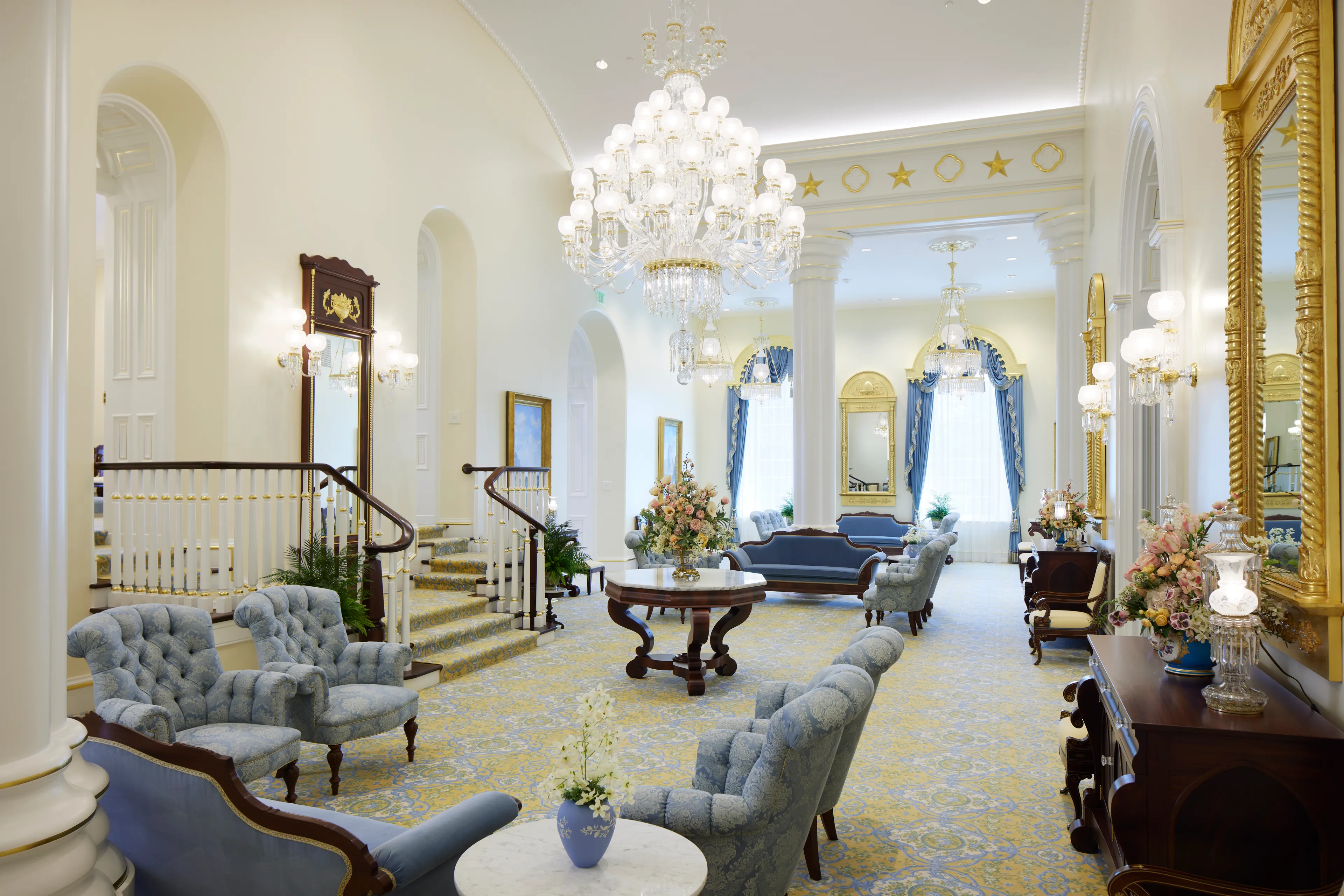 Interior image of the St. George Utah Temple. The image features the Celestial Room. There is a chandelier in the room with chairs and couches. There are gilded mirrors in the room. 