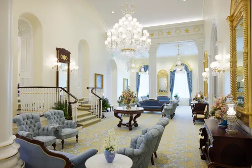 Interior image of the St. George Utah Temple. The image features the Celestial Room. There is a chandelier in the room with chairs and couches. There are gilded mirrors in the room. 