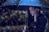 woman on the phone with umbrella under the rain