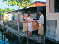 A woman and her daughter delivering a basket to another woman in the Philippines.