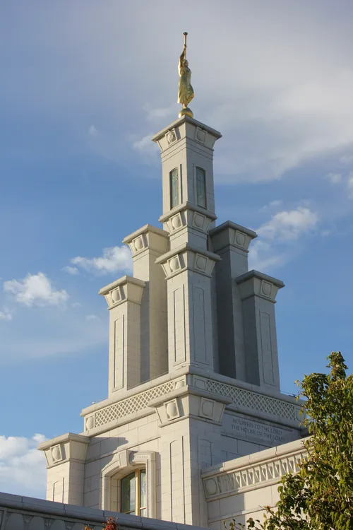 The spire of the Columbia River Washington Temple, with the angel Moroni in front of a patch of thin white clouds.