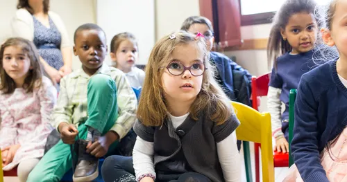 Primary-age children sit while watching an activity.