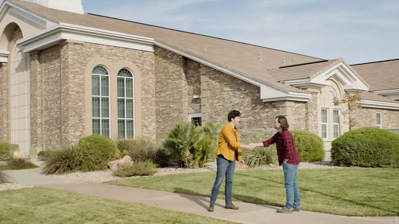 Two men greet each other outside of a church building