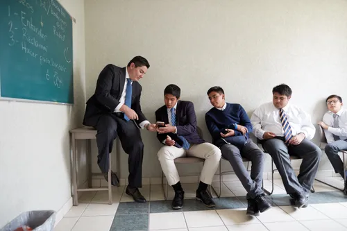 young men sit in a classroom and listen to their Priesthood instructor