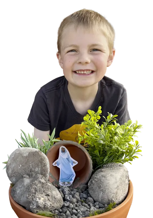 Smiling boy with a diorama of the resurrected Savior in front of the tomb
