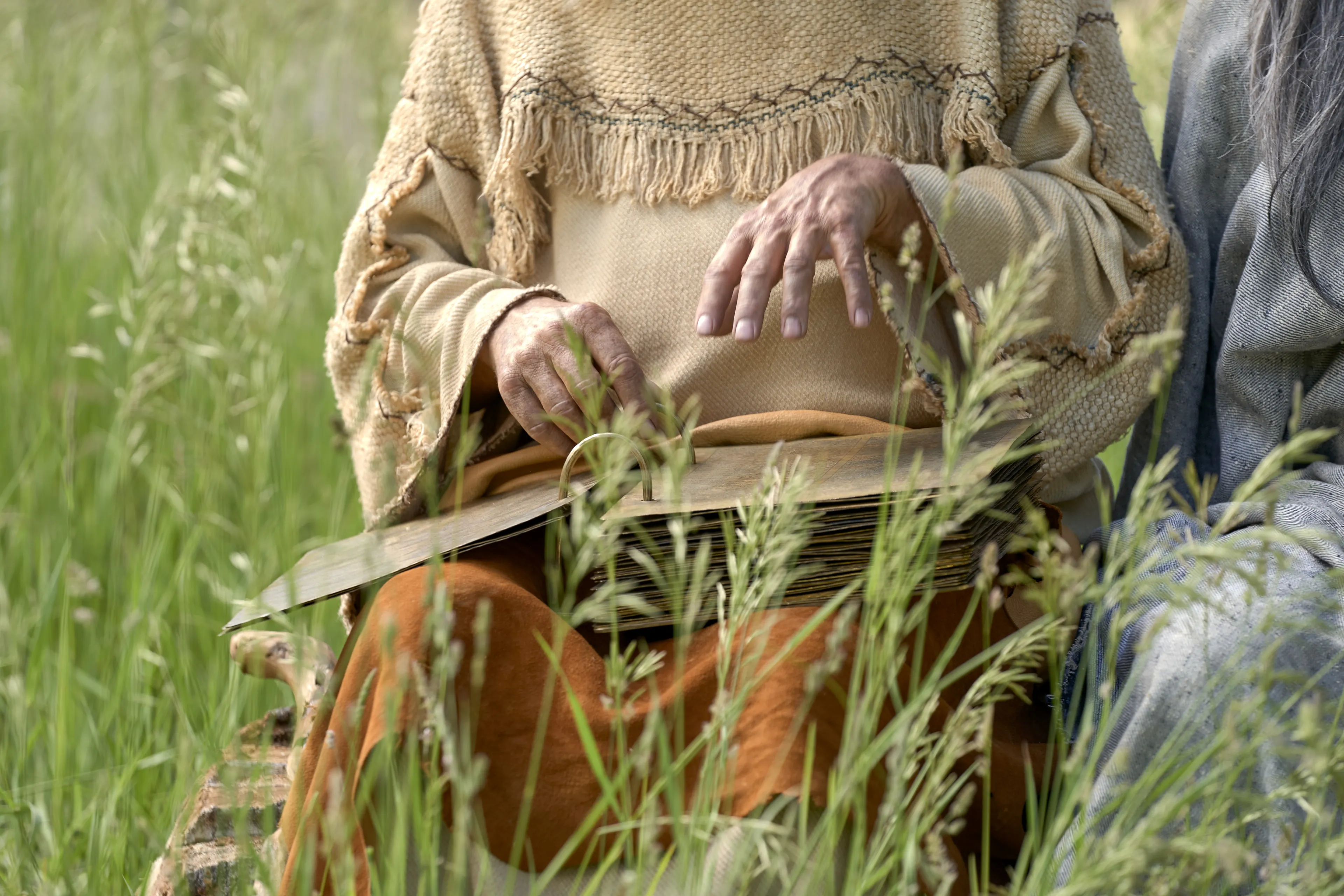 Lehi holds the plates while teaching his family.