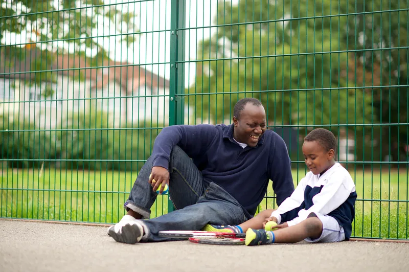 A father holds his son while walking down a forest trail