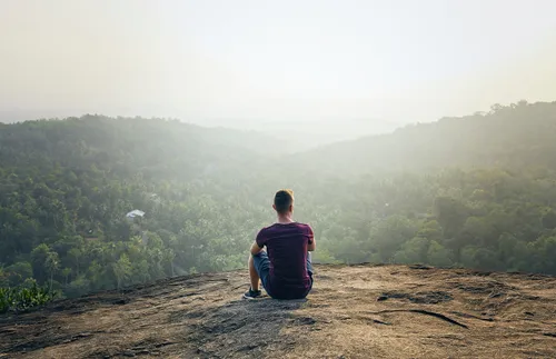 man sitting on top of rock