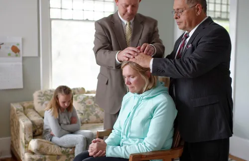 woman receiving a priesthood blessing in home
