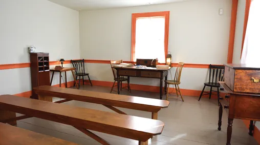 An upper room in the John Johnson home in Hiram, Ohio, filled with long benches and several desks.