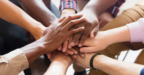 hands with different skin colors on top of each other in a circle