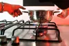 hands holding a pan on a lighted oven