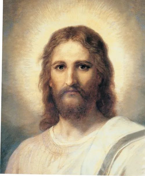 Frontal head and shoulders portrait of Jesus Christ. Christ is depicted wearing a pale red robe with a white and blue shawl over one shoulder. Light emanates from His face.