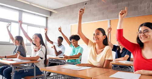 young people raising hands in school