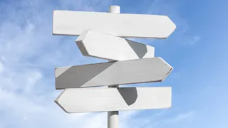 Blank white signpost with multiple directions on blue sky background