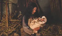 Mary holds the newborn Jesus Christ in a stable
