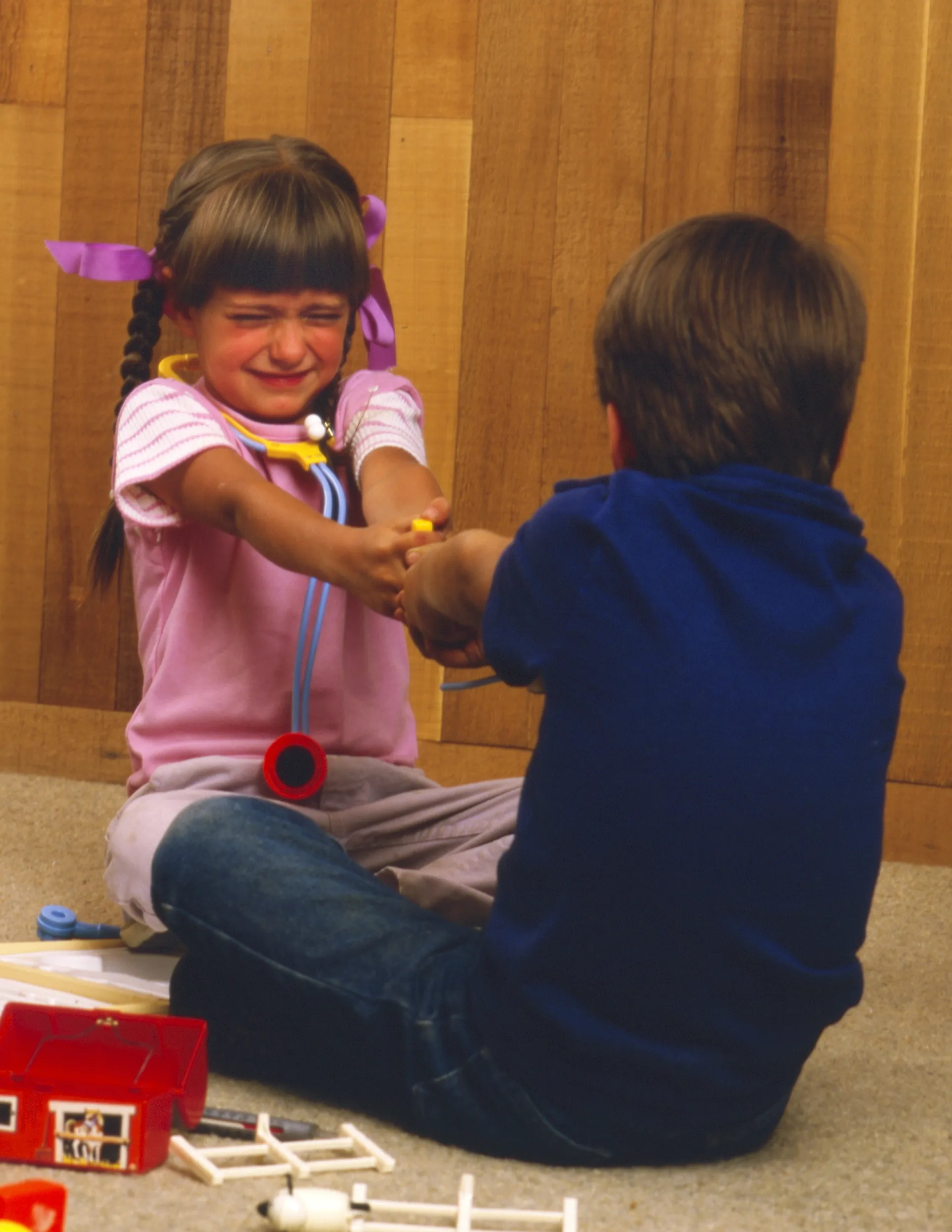 A little boy and a little girl fighting over a toy.