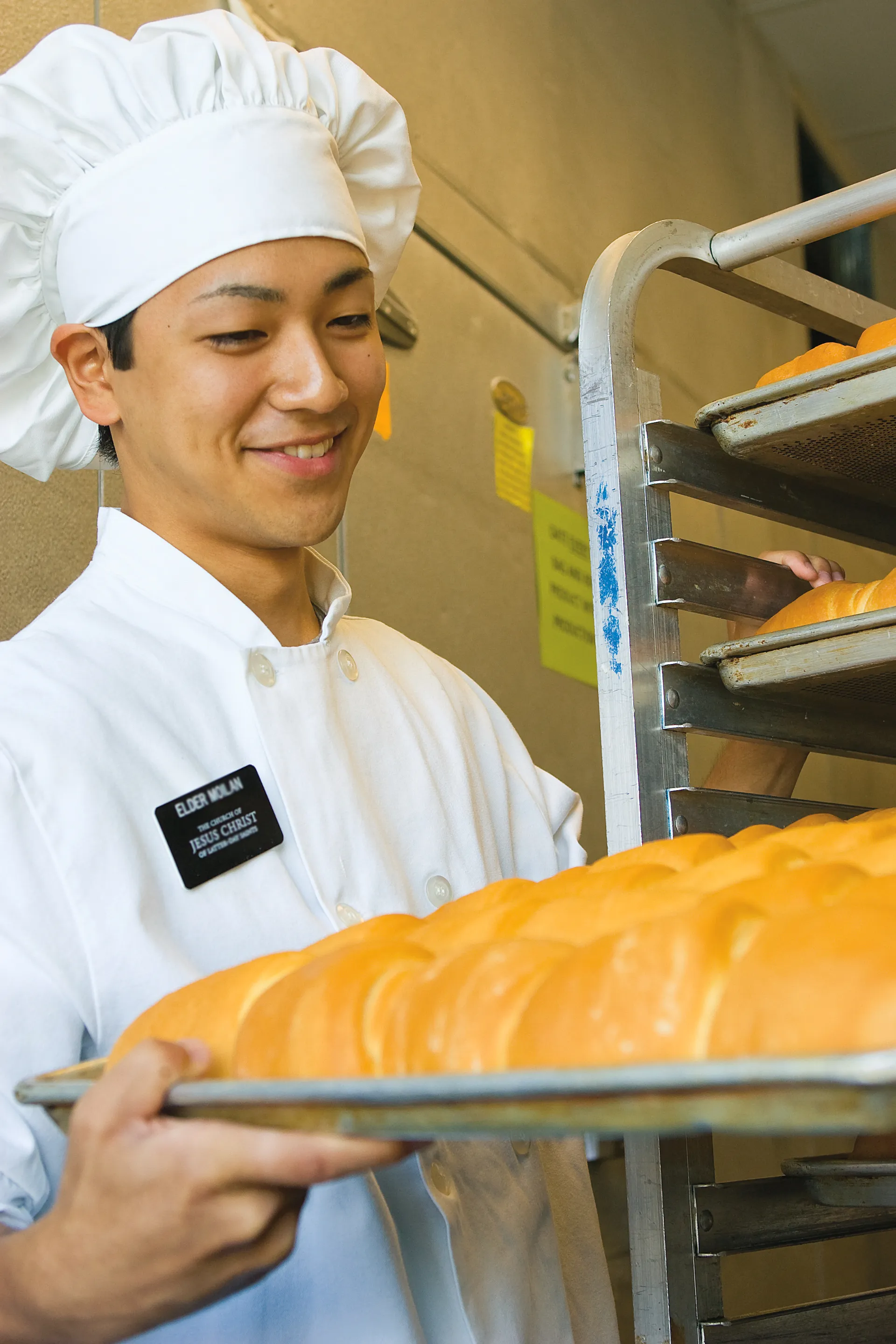 An elder missionary in a white apron and hat serving in a bakery.