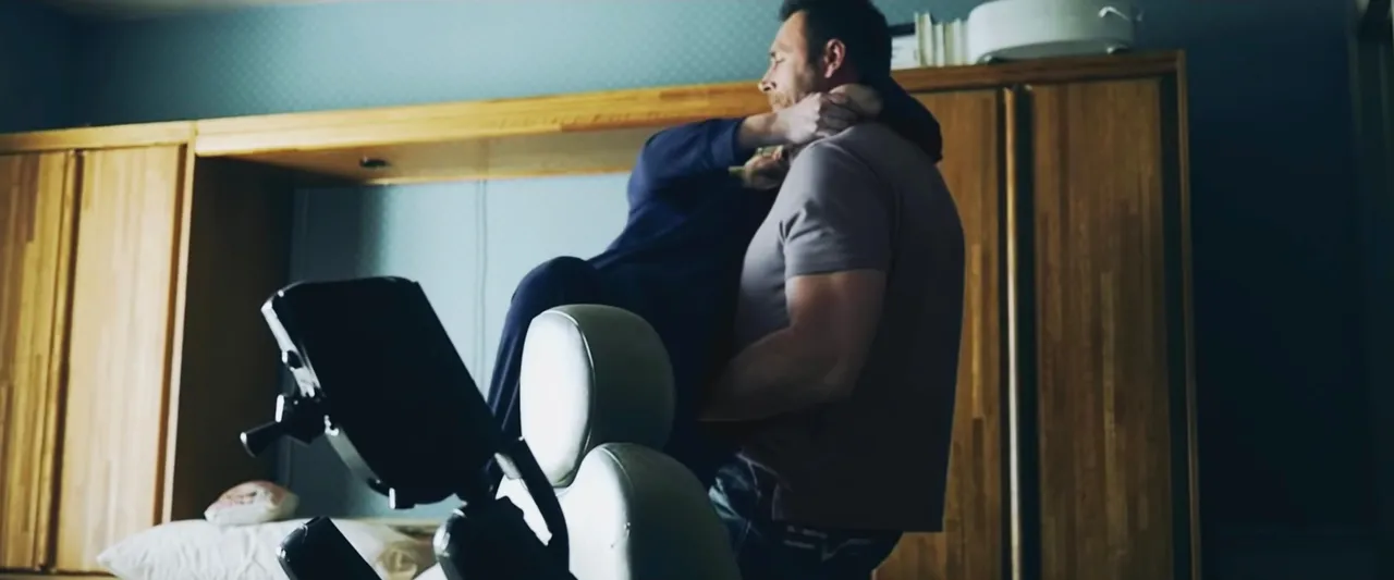 A man helps his neighbor get into a wheel chair