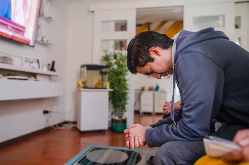 man praying in his living room