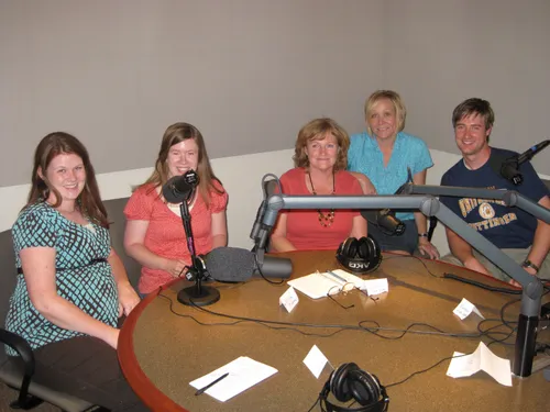 A group of people sitting at microphones around a table.