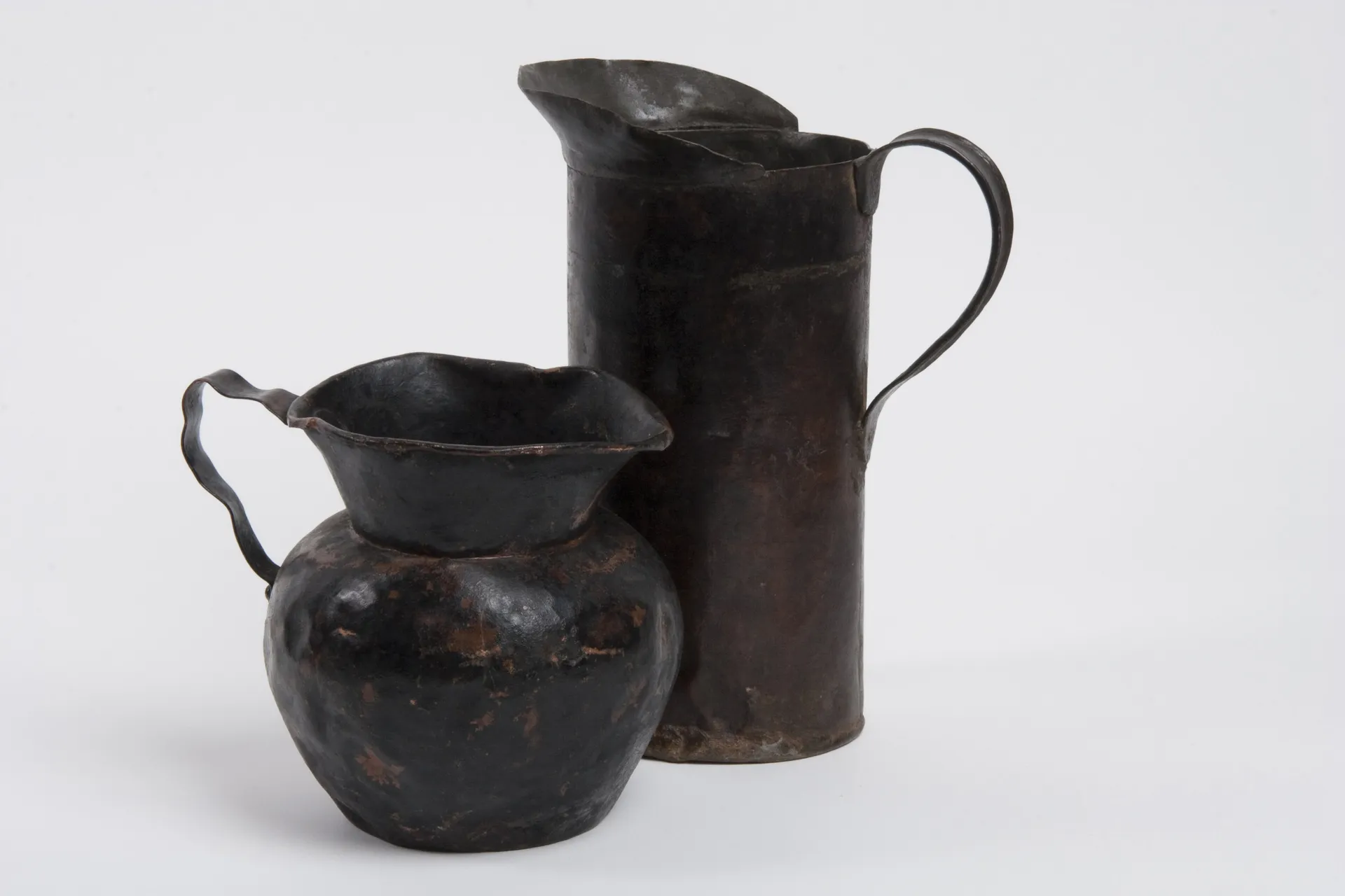 A photograph of two aged metal pitchers.