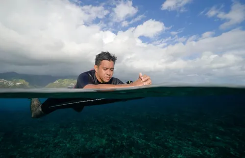 man praying while in the water on a surfboard