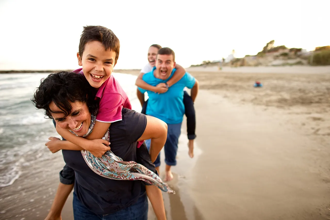 Parents give their kids a piggy back ride at the beach