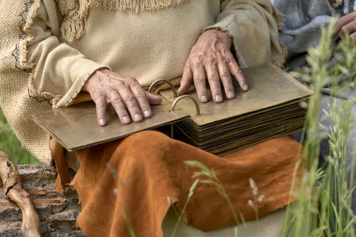 Lehi holds the plates while teaching his family.