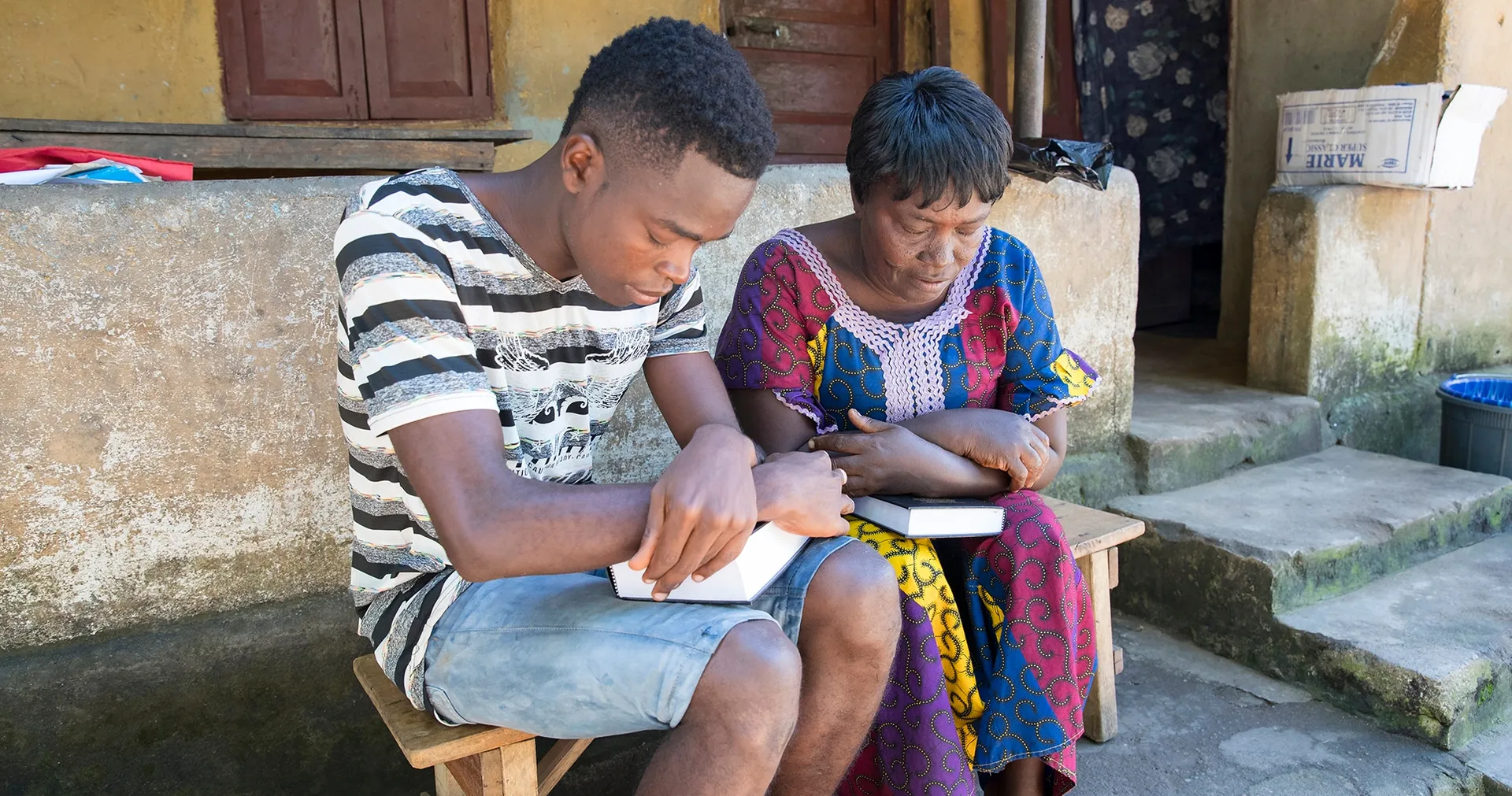 Mother and son pray with scriptures in hand.