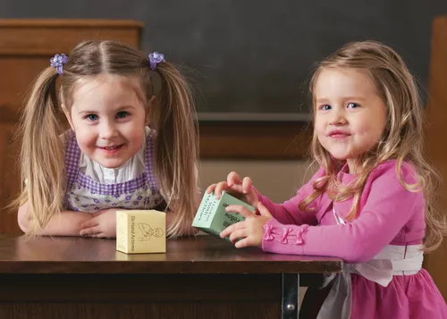 two young girls standing by table 